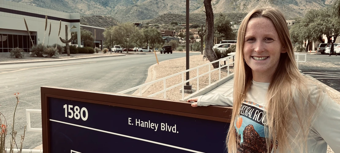 Katherine Liccione poses in front of the "College of Veterinary Medicine" sign, against an overcast mountain background.