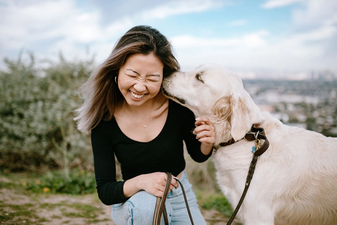 Girl being licked by her dog.