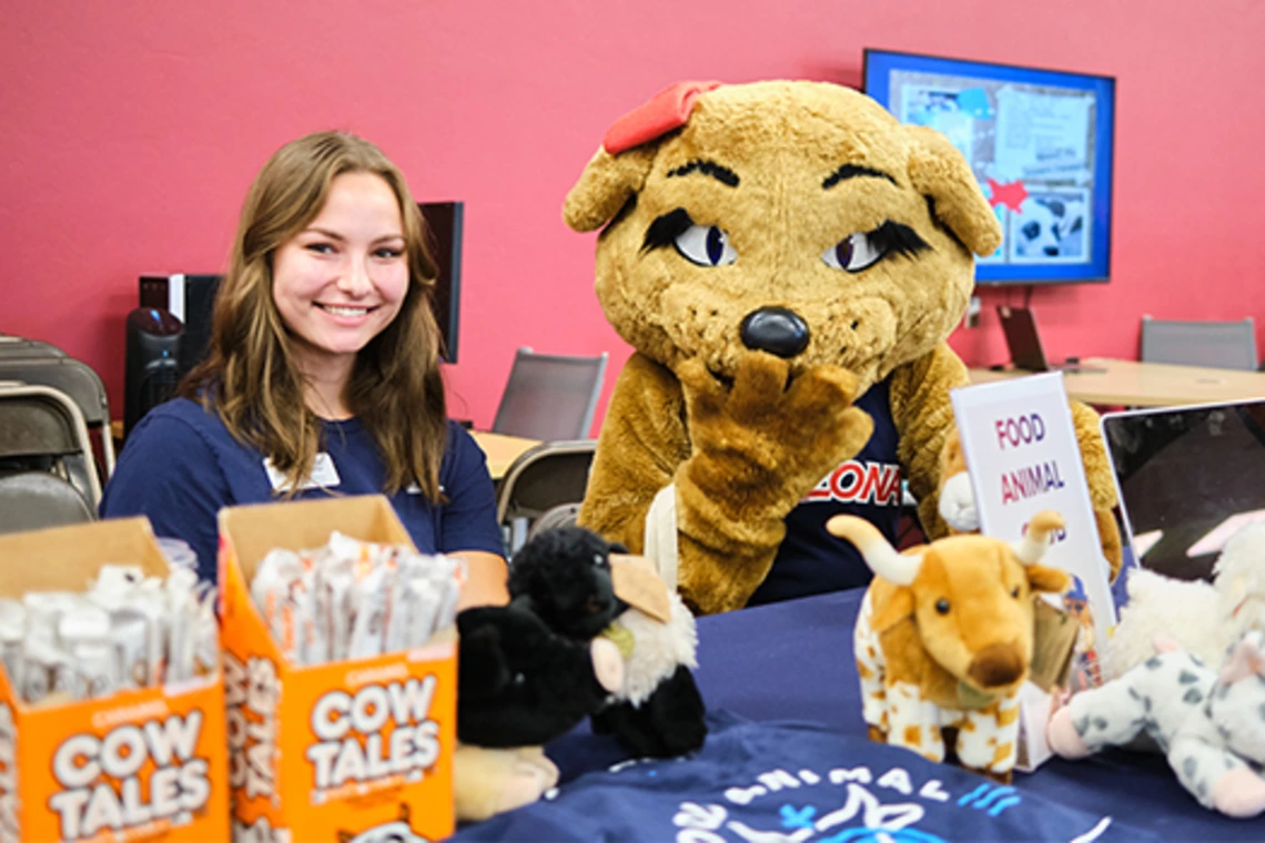Student sitting with mascot and smiling